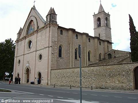 Basilica of Santa Chiara in Assisi, pink stone facade with rose windows and visitors