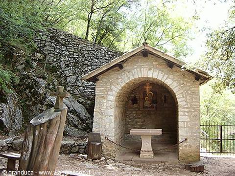 Small stone chapel with altar and wooden cross in the woods, Eremo delle Carceri, Assisi