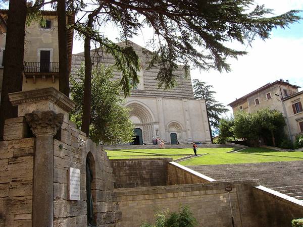 Spoleto Cathedral: Romanesque facade among trees, stone staircase and green lawn