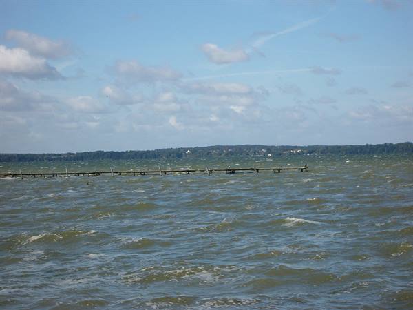 Choppy waters with a long wooden pier, blue sky with scattered clouds