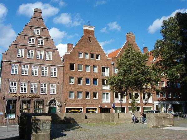 Stepped-gable brick houses in Hamburg, blue sky, people sitting nearby