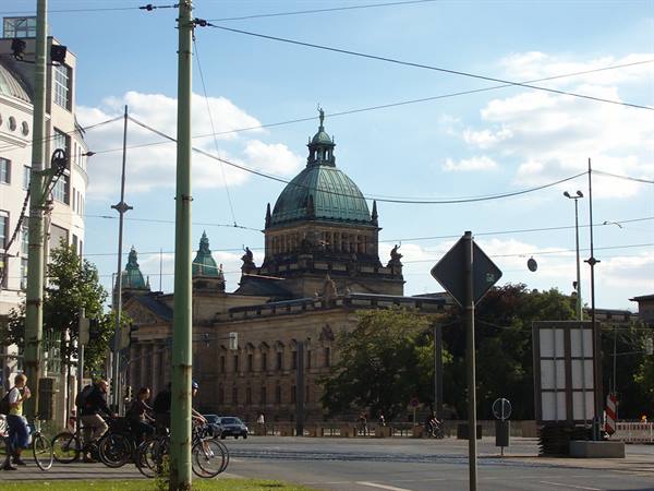 Cyclists cross the intersection in front of the green-domed Federal Administrative Court in Leipzig