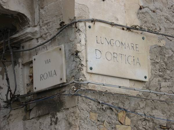 Marble street signs Via Roma and Lungomare d'Ortigia on old stone wall