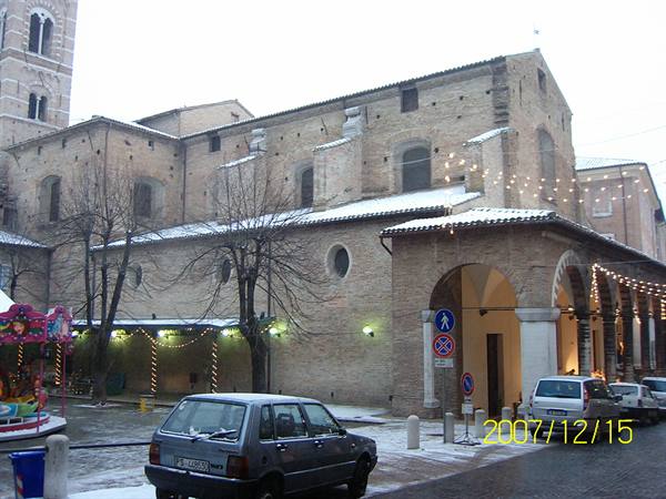 Brick church with arched portico, snow on roofs, parked cars