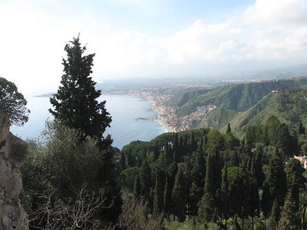 Blue bay with coastal town, green hills and cypress trees, Taormina