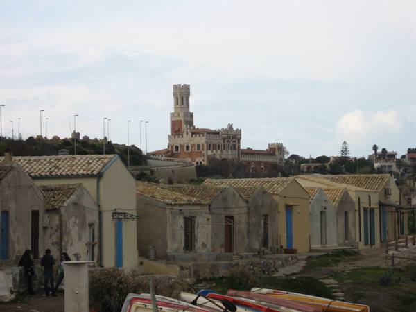 Old fishermen houses with tiled roofs and boats, castle in background