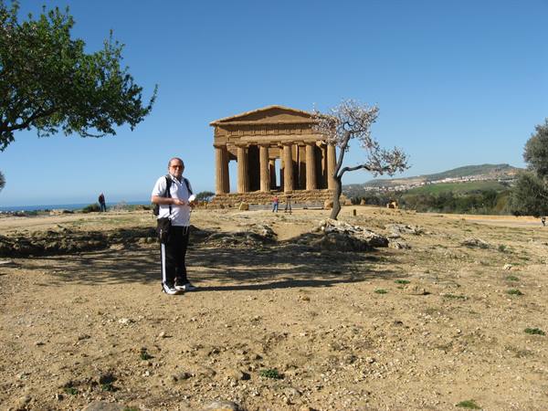 Tourist in front of the Temple of Concordia in Agrigento, golden stone in sunlight