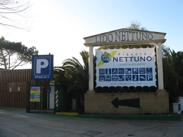 Entrance to Lido Nettuno: white sign on stone pillar, 24h parking sign