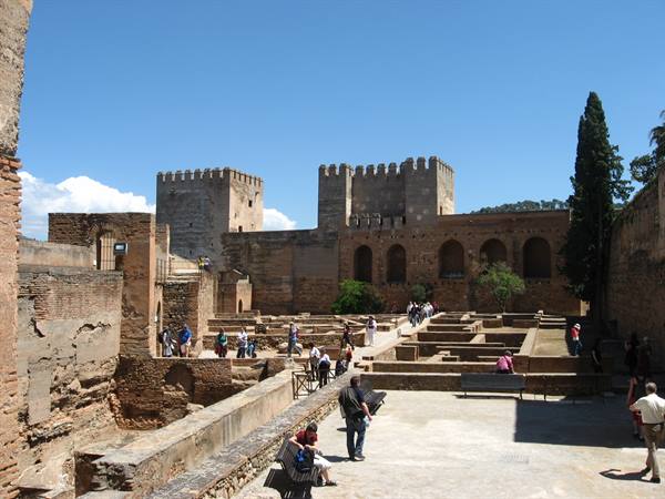 Tourists walking among the walls and towers of Granada's Alhambra in sunshine
