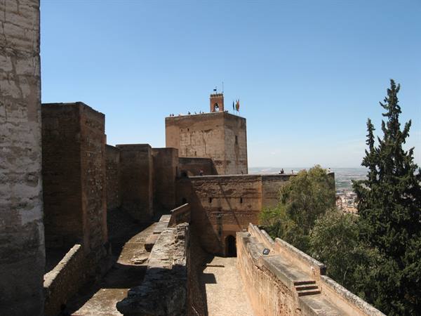 Red brick watchtower of the Alhambra with visitors on the terrace, blue sky