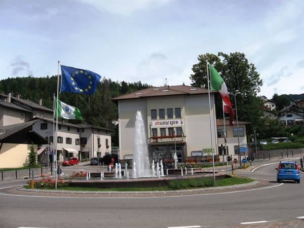 Roundabout fountain in front of the town hall, EU and Italian flags waving