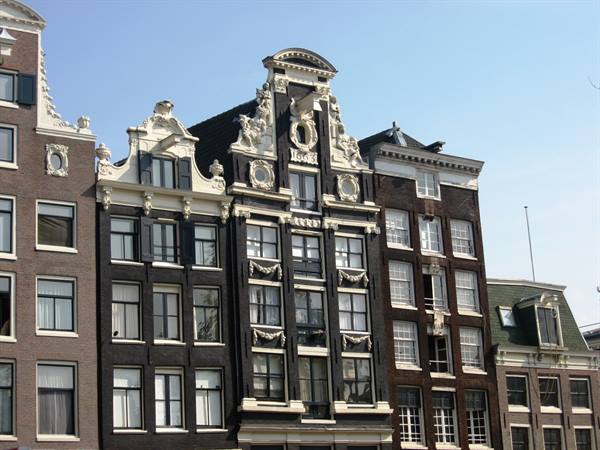 Amsterdam canal houses with ornate baroque gables under a clear blue sky