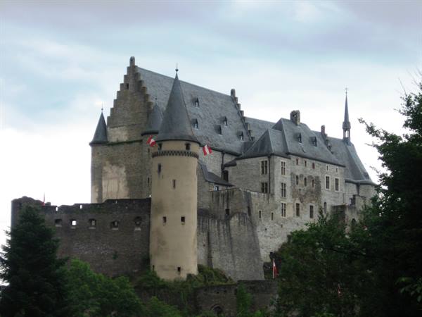 Vianden Castle with stone towers and conical roofs among trees