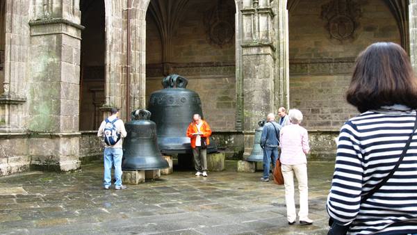 Tourists admire the huge bronze bells in Santiago cathedral's cloister