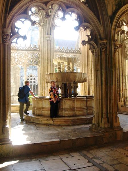 Tourists beside the gothic stone fountain in Batalha monastery cloister