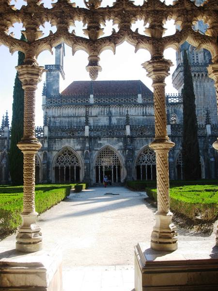 Carved stone cloister of Batalha Monastery, twisted columns and green hedges