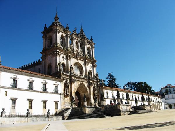 Baroque facade of Alcobaça Monastery under blue sky, stone staircase