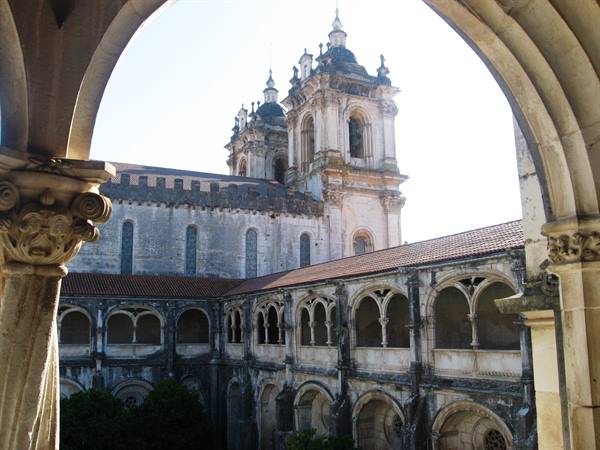 Cloister and baroque towers of the Convent of Christ in Tomar, framed by stone arches