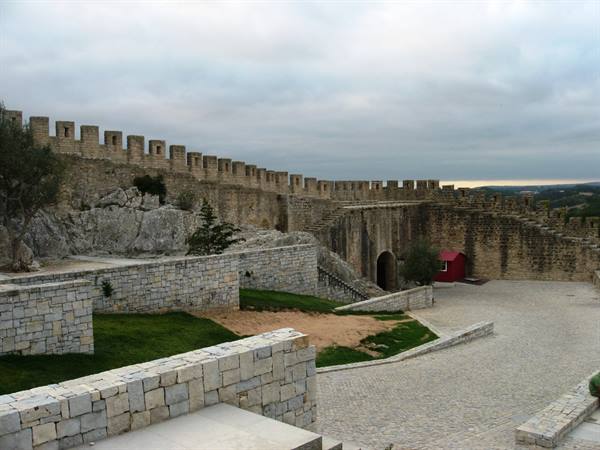 Stone crenellated walls of Sesimbra castle under a cloudy sky
