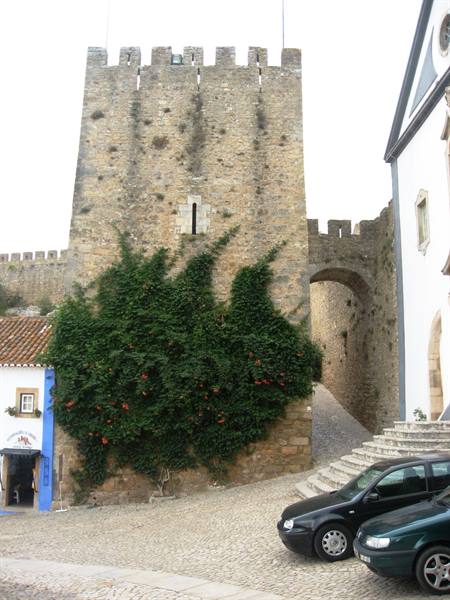 Óbidos castle, stone tower with climbing ivy, parked cars below