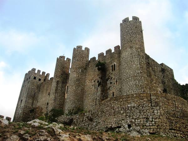 Óbidos castle, crenellated stone towers under a cloudy sky
