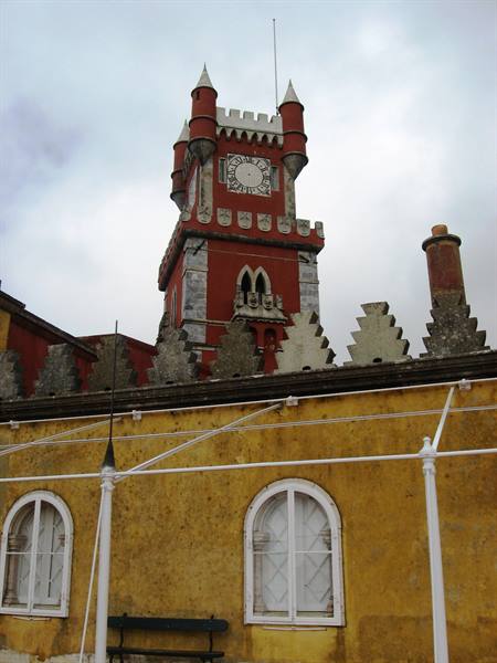 Red clock tower of Pena Palace above yellow wall in Sintra