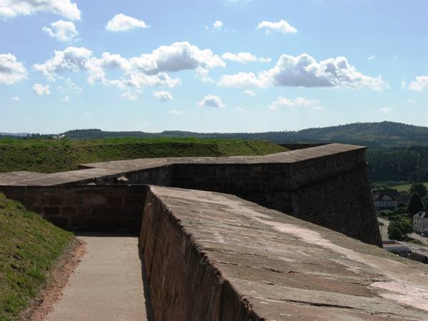 Stone ramparts of Rosenberg Fortress under white clouds in Kronach