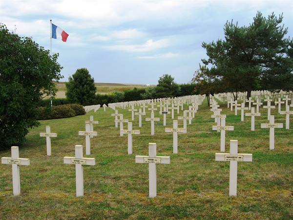 French military cemetery with white wooden crosses and flag waving above