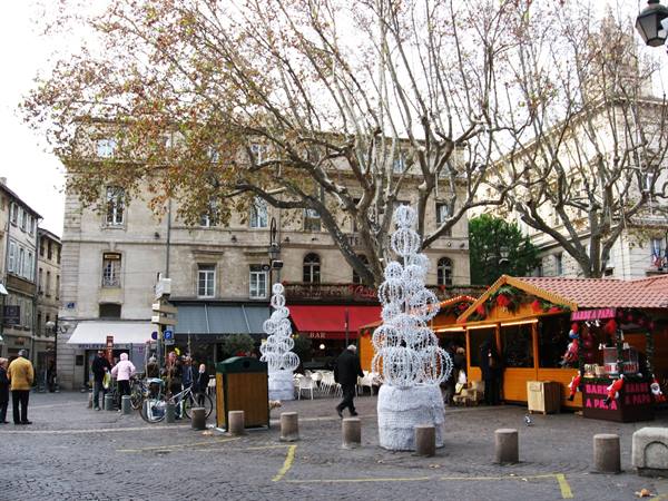 Town square with wooden Christmas market stalls and light decorations, Avignon
