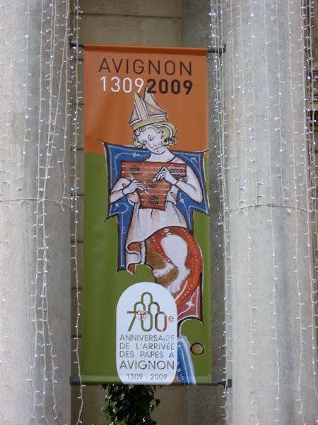 Orange and green banner marking 700 years of the Avignon popes, between columns and fairy lights