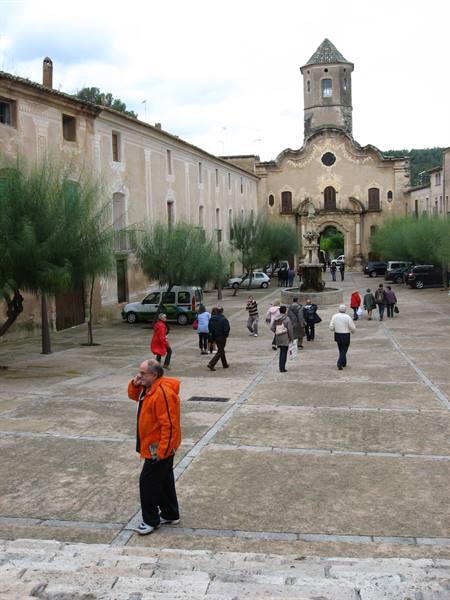 Visitors walk across a sanctuary courtyard, man in orange jacket in foreground