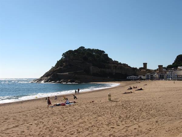 Tossa de Mar beach, people sunbathing beneath the hilltop towers