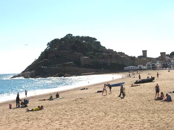 Tourists on the sandy beach below Tossa de Mar castle