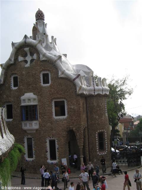 Gaudí's stone house with wavy tiled roof at Park Güell, tourists below