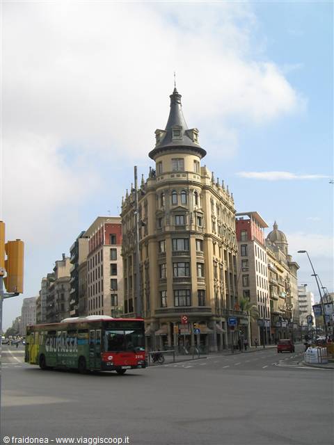 City bus crossing in front of modernist building with conical tower, Barcelona