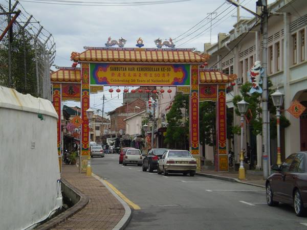 Colorful Chinese archway over Jonker Street entrance in Malacca, parked cars below
