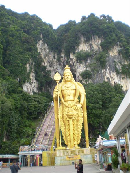 Golden Murugan statue at Batu Caves, tourists photographing below the staircase