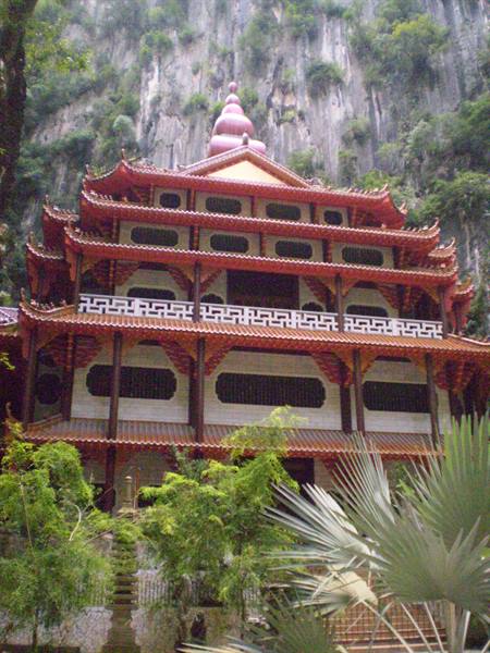 Red multi-tiered Chinese temple beneath a limestone cliff, Ipoh