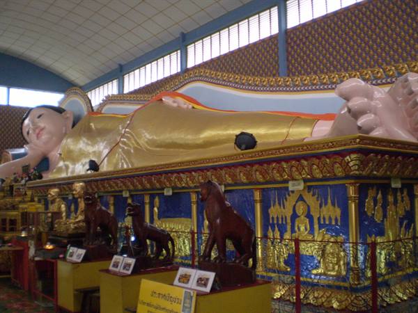 Golden reclining Buddha inside a temple hall, blue and gold decorated base