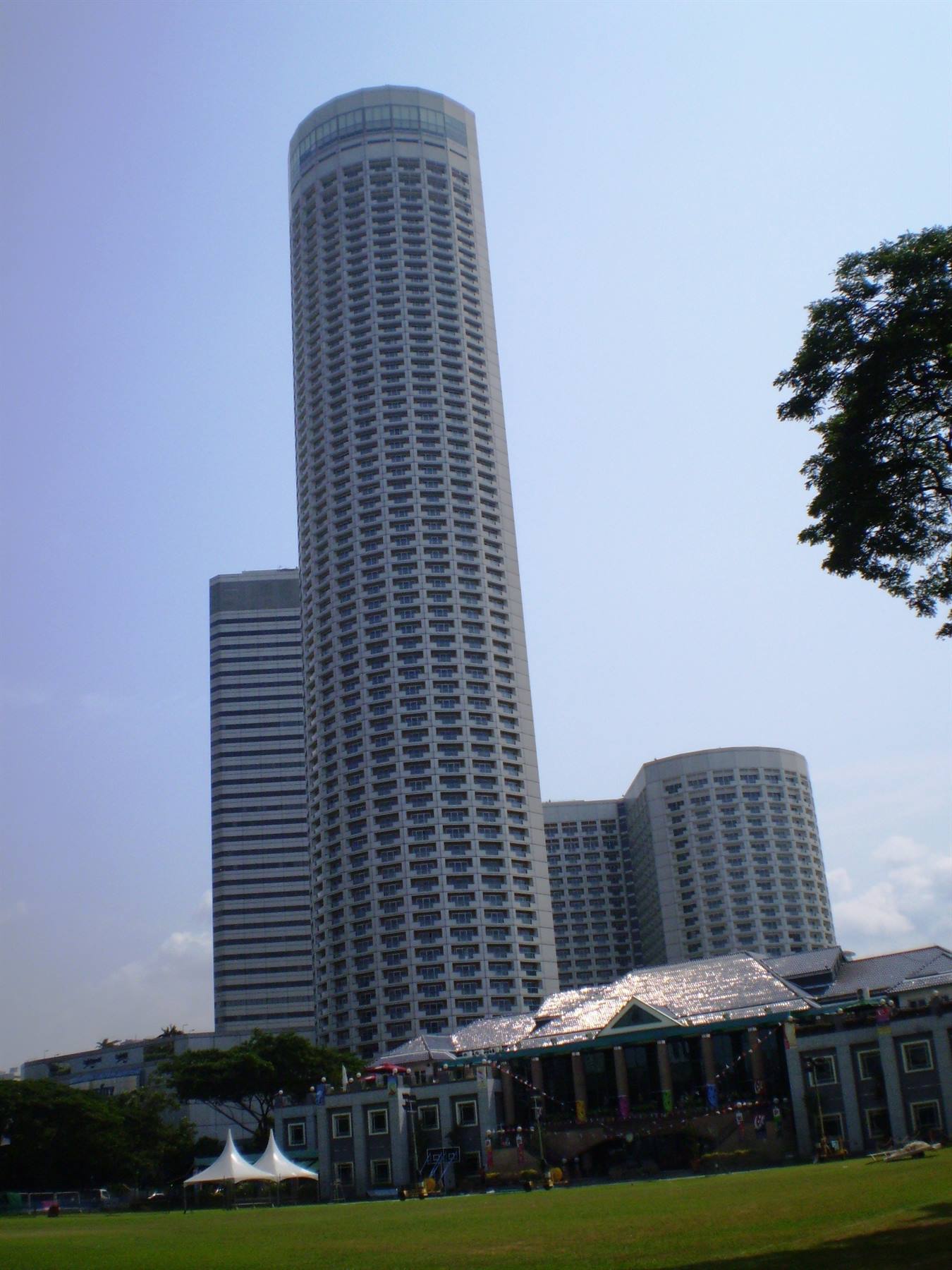 The cylindrical Swissôtel The Stamford tower rises over the park under a clear sky