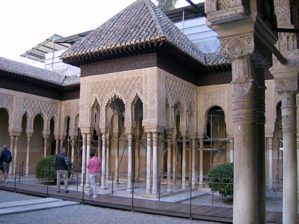 Tourists in the Alhambra Court of the Lions among carved columns and arches