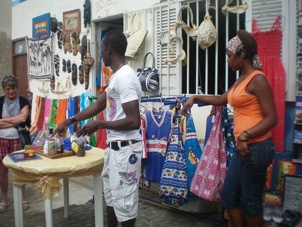 Souvenir market stall: vendor with masks, colorful fabrics and handicrafts displayed