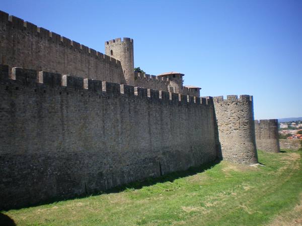 Stone ramparts with battlements and towers of Carcassonne under blue sky