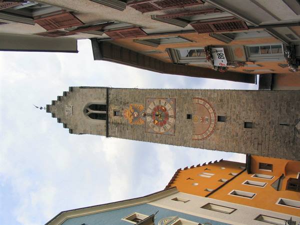 Zwölferturm tower in Vipiteno among colorful houses, painted clock on stone