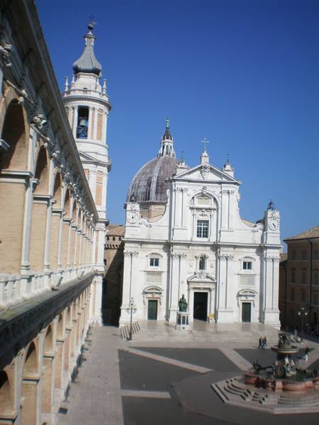 Loreto, white basilica facade with dome, bell tower and bronze fountain