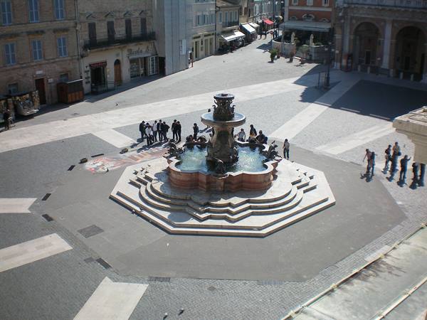Tourists gather around the marble baroque fountain in the town square