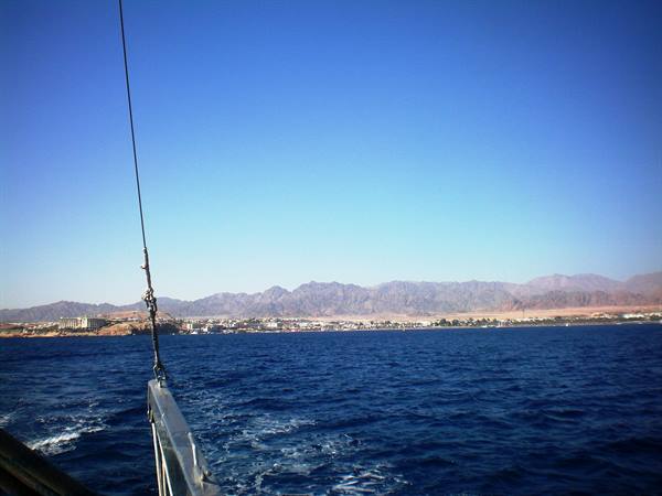 Metal boat bow cutting the Red Sea toward Sharm el-Sheikh shoreline