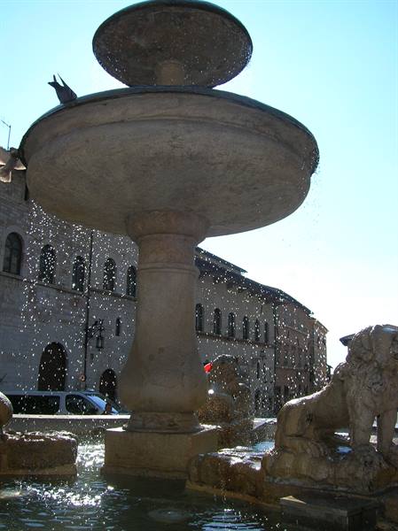 Fontana Maggiore fountain in Assisi, stone basins and carved lions, water sparkling in sunlight