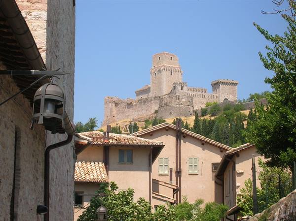 Rocca Maggiore fortress towers above terracotta rooftops in Assisi under blue sky