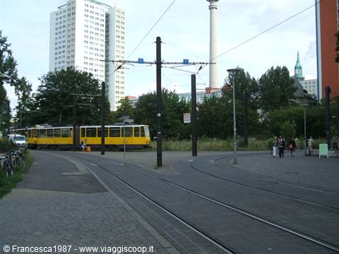 Yellow tram on tracks near Alexanderplatz, TV tower in the background
